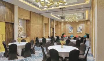 Function room with round banquet tables, black chair covers and chandeliers