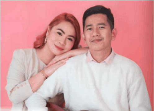 Glynis and Anton posing together against a pink backdrop, Anton holding a guitar