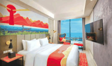 Junior Suite Room with red-accented bed, artwork mural and sea-view window